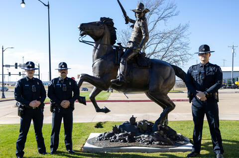 Chickasaw Lighthorse Officers Wes Harden, Jerald McDonald and Dalton Reed stand with the bronze, largerthan-life Chickasaw Lighthorse monument created by artist James Blackburn.