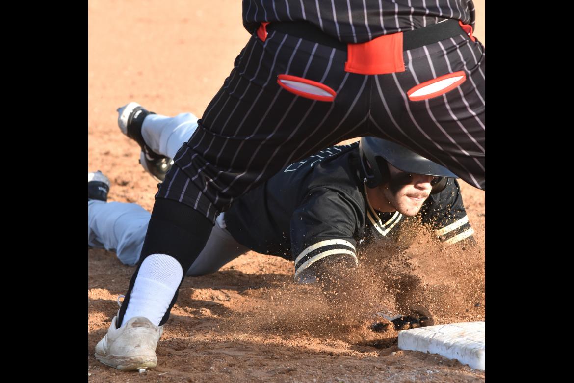 Coyt Bell dives back to first to avoid the tag in the season opener Saturday 